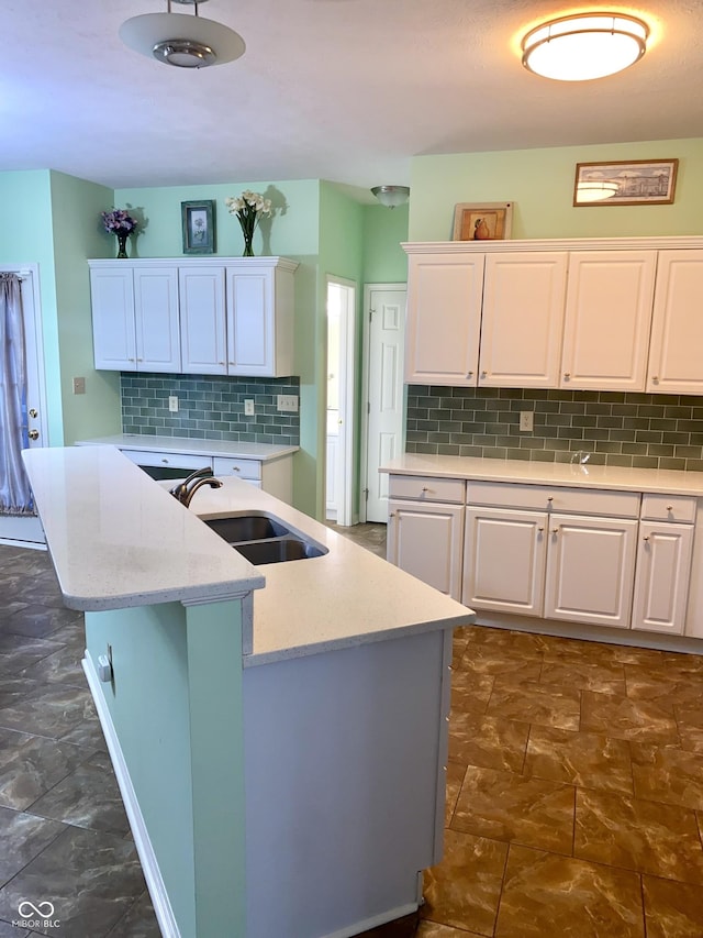 kitchen with sink, white cabinetry, light stone counters, an island with sink, and decorative backsplash