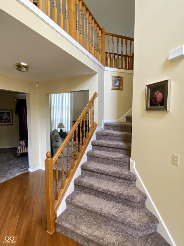 stairs with a towering ceiling and hardwood / wood-style floors