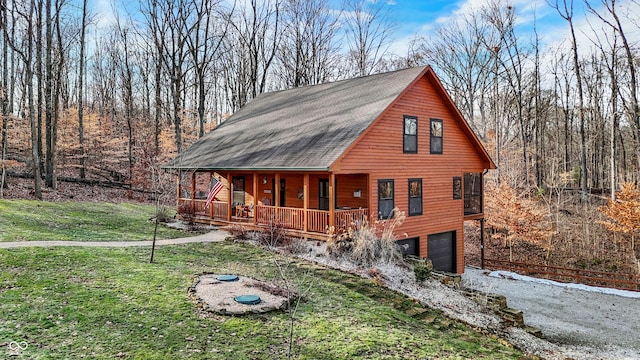 cabin with a garage, a porch, and a front lawn