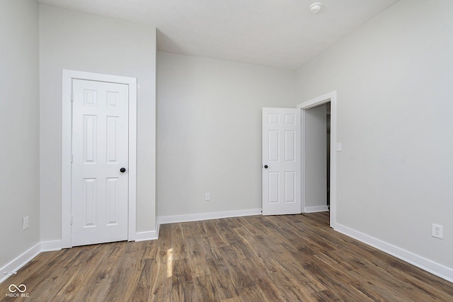 unfurnished bedroom featuring baseboards and dark wood-type flooring