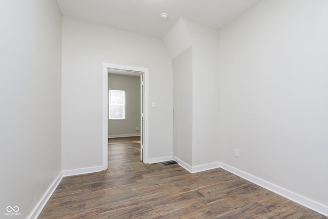 unfurnished room featuring dark wood-style flooring, visible vents, and baseboards