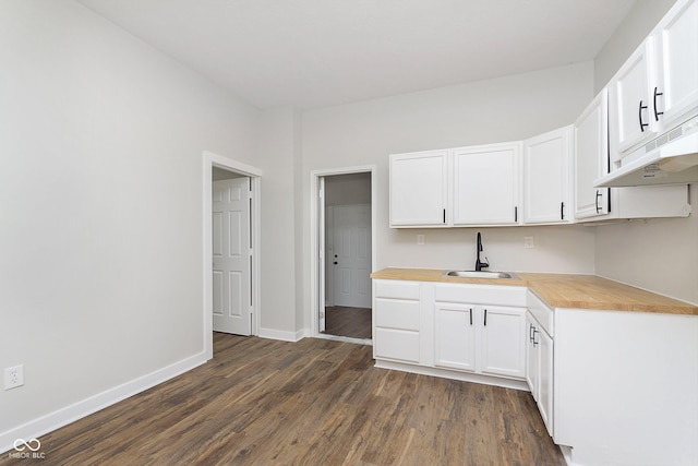 kitchen with dark wood finished floors, a sink, white cabinetry, and under cabinet range hood