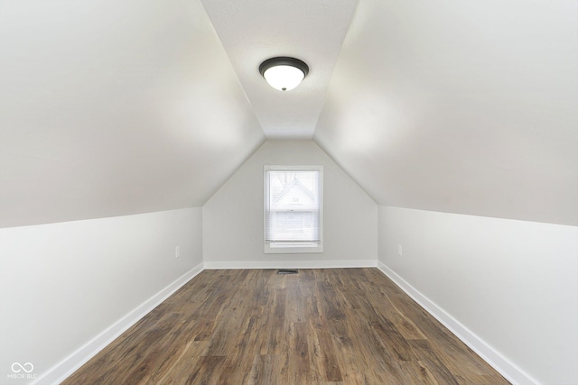 bonus room with dark hardwood / wood-style floors and vaulted ceiling