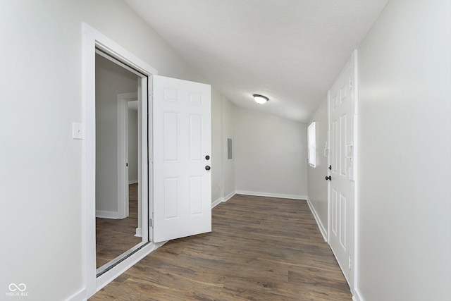 hallway with dark wood-type flooring, vaulted ceiling, and baseboards