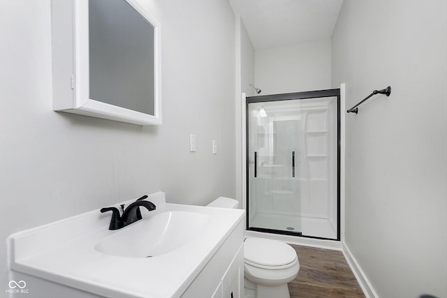 bathroom featuring baseboards, toilet, wood finished floors, vanity, and a shower stall