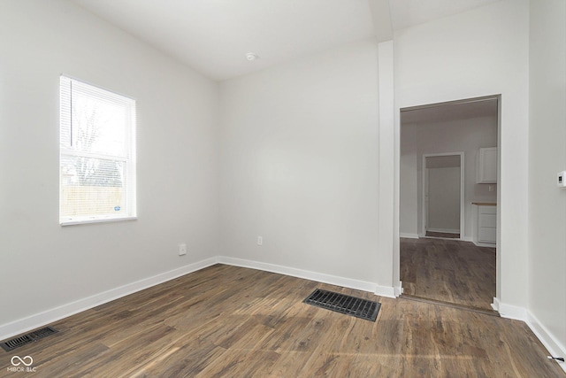 spare room with visible vents, dark wood finished floors, and baseboards