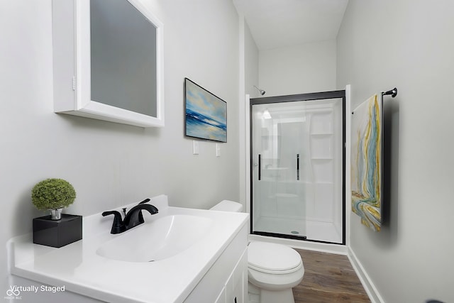 bathroom featuring wood finished floors, vanity, toilet, and a shower stall