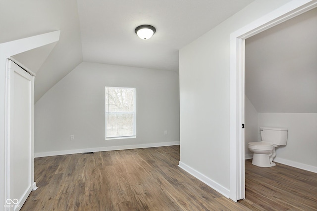 additional living space featuring lofted ceiling, baseboards, and dark wood-style flooring