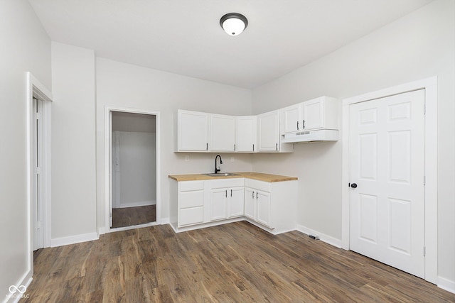 kitchen featuring butcher block counters, dark wood-style flooring, white cabinets, and a sink