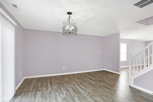 empty room featuring dark hardwood / wood-style floors and a notable chandelier