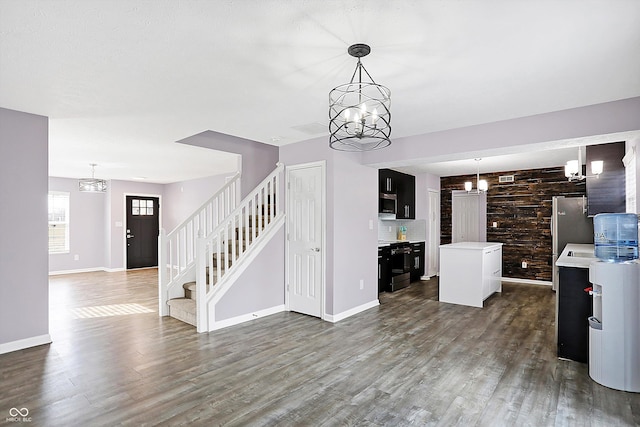 unfurnished living room with dark wood-type flooring and an inviting chandelier