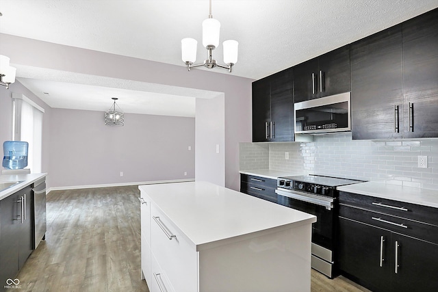 kitchen with hanging light fixtures, a kitchen island, appliances with stainless steel finishes, and an inviting chandelier