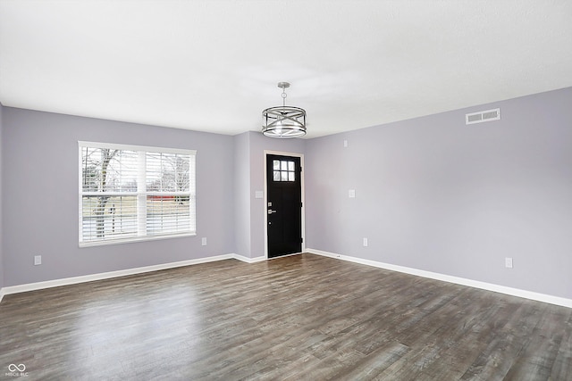 entryway with dark wood-type flooring and a notable chandelier