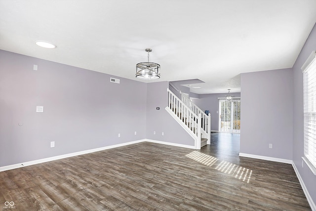 spare room with dark hardwood / wood-style floors, a wealth of natural light, and a notable chandelier