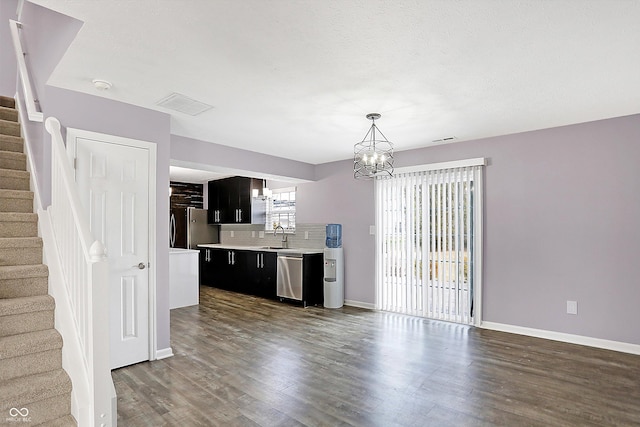 unfurnished living room featuring sink, a notable chandelier, dark wood-type flooring, and a textured ceiling