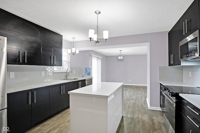 kitchen featuring range with electric cooktop, a kitchen island, sink, and decorative light fixtures