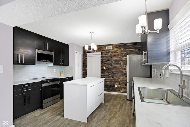 kitchen featuring sink, electric range oven, a center island, decorative light fixtures, and a chandelier