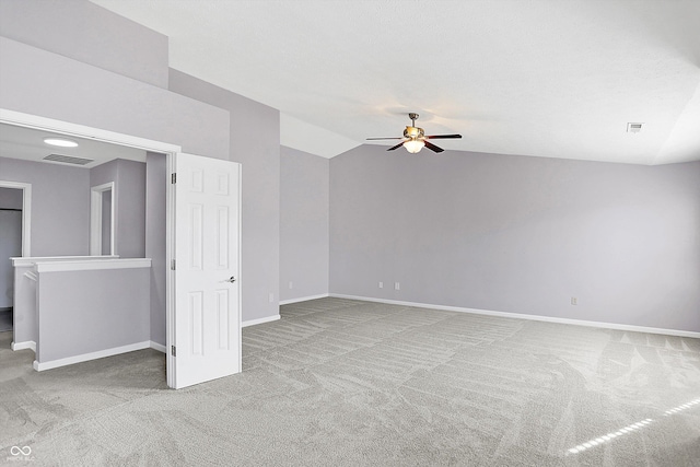 carpeted spare room featuring ceiling fan, vaulted ceiling, and a textured ceiling