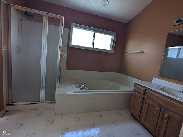 bathroom with vanity, independent shower and bath, vaulted ceiling, and a textured ceiling