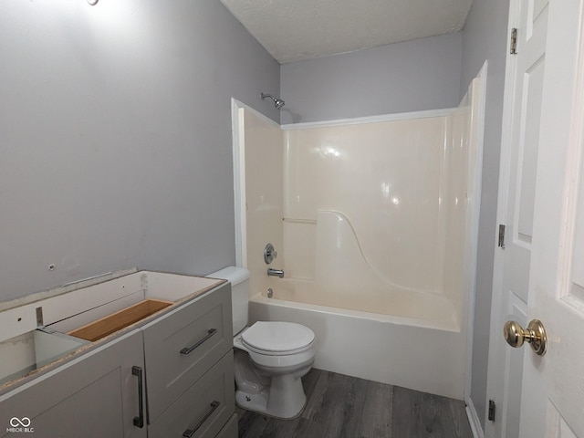 bathroom featuring hardwood / wood-style flooring, bathtub / shower combination, toilet, and a textured ceiling