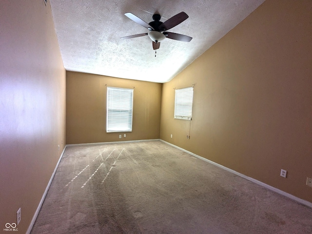 spare room featuring ceiling fan, lofted ceiling, light colored carpet, and a textured ceiling