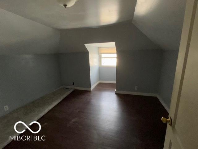 additional living space featuring lofted ceiling and dark hardwood / wood-style flooring