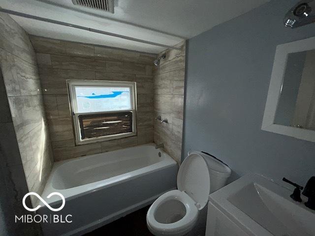 full bathroom featuring sink, tiled shower / bath combo, and toilet