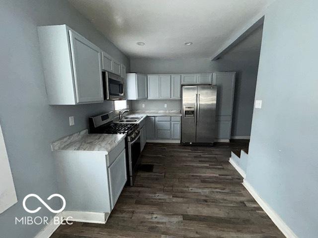 kitchen featuring appliances with stainless steel finishes, sink, white cabinets, and dark hardwood / wood-style flooring