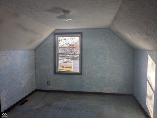 bonus room with vaulted ceiling, a textured ceiling, and carpet