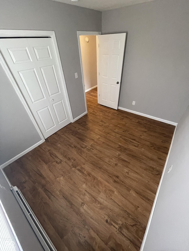 unfurnished bedroom with a closet, baseboards, and wood finished floors