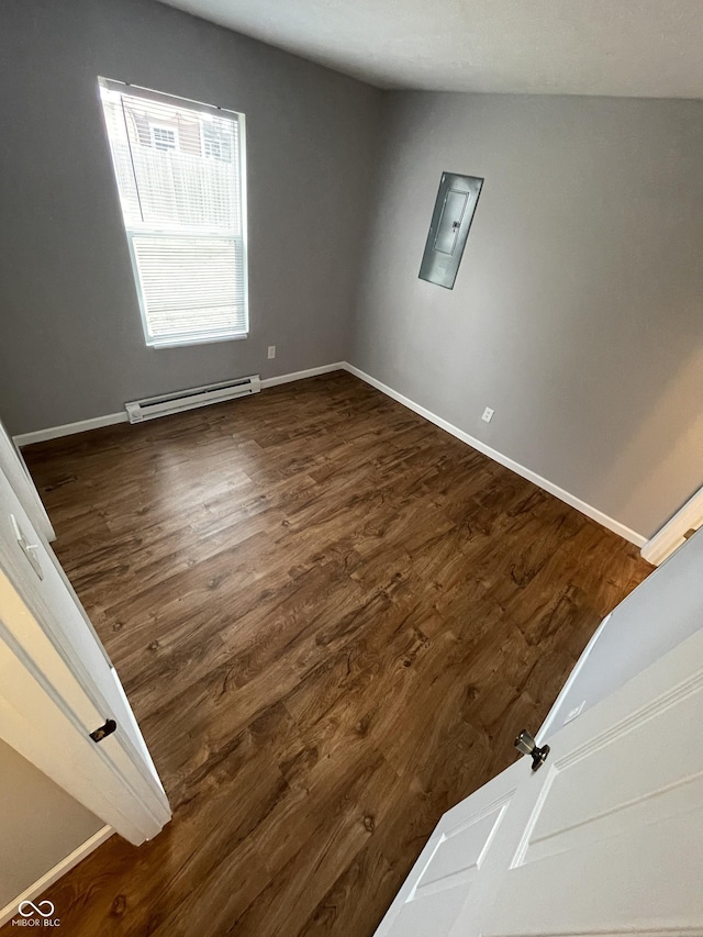 empty room featuring a baseboard heating unit, baseboards, and dark wood-style floors