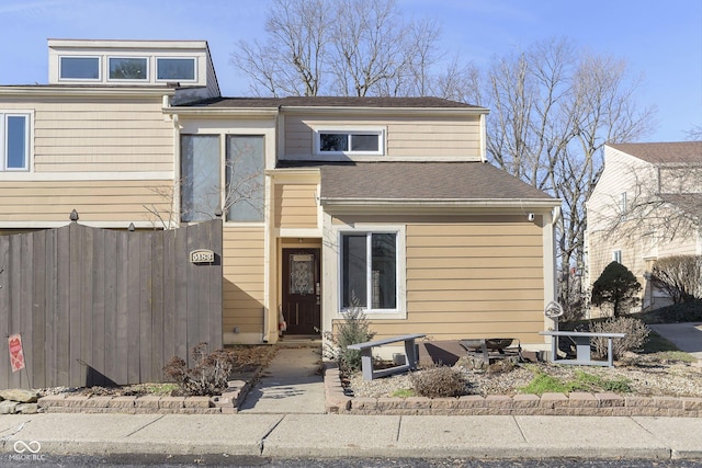 view of front of house featuring roof with shingles and fence