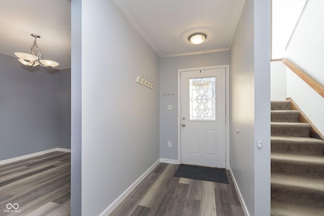 doorway featuring dark wood-style floors, a chandelier, stairs, and baseboards