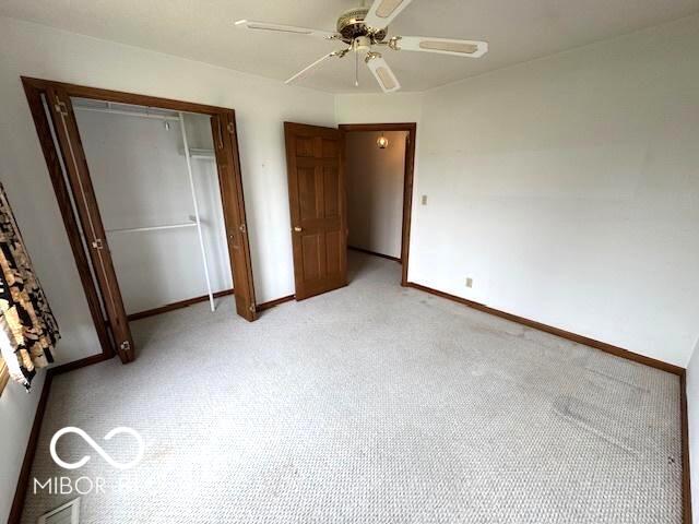 unfurnished bedroom featuring light carpet, a closet, and ceiling fan