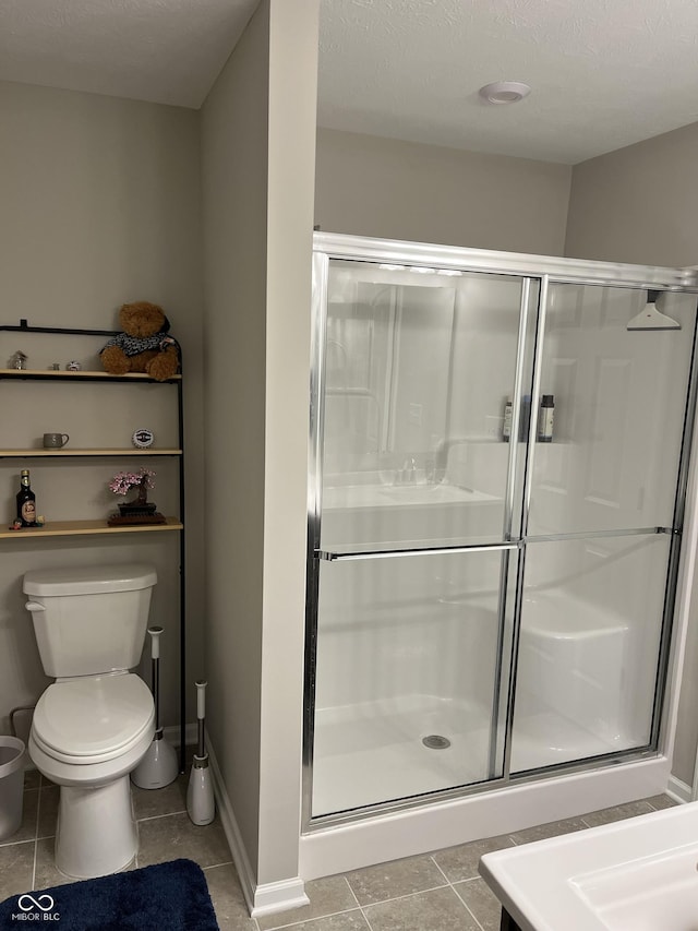 bathroom featuring tile patterned floors, a shower with door, and toilet