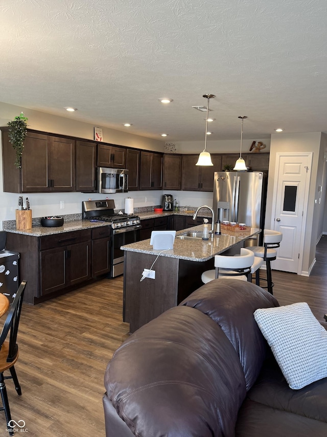 kitchen with hanging light fixtures, sink, an island with sink, and appliances with stainless steel finishes