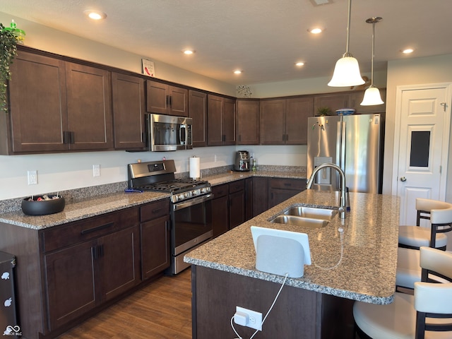 19438 Astoria Ave, Sheridan, IN 46069 - kitchen with appliances with stainless steel finishes, a sink, a breakfast bar area, dark brown cabinets, and dark wood-style floors
