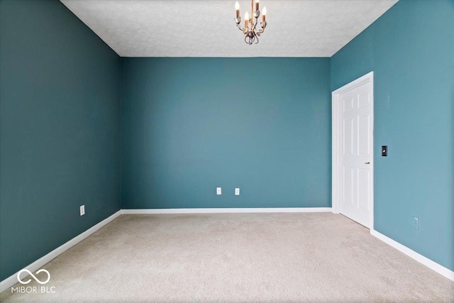 unfurnished room with carpet floors, a notable chandelier, and a textured ceiling