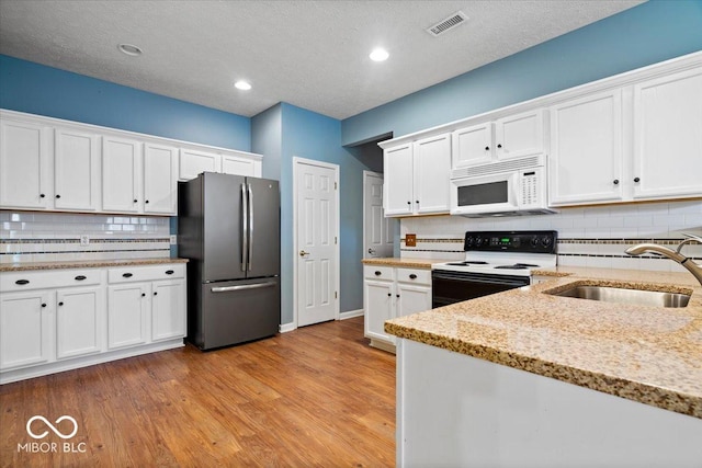 kitchen featuring sink, white cabinetry, electric range oven, stainless steel refrigerator, and light stone countertops