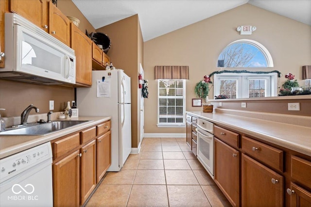 kitchen with a healthy amount of sunlight, sink, light tile patterned floors, and white appliances