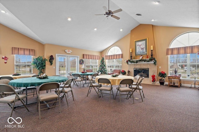 carpeted dining area featuring a fireplace, high vaulted ceiling, french doors, and ceiling fan