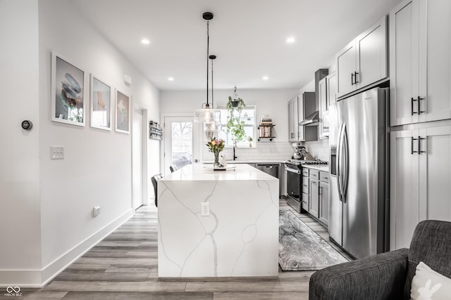 kitchen with light stone counters, tasteful backsplash, decorative light fixtures, a center island, and stainless steel appliances