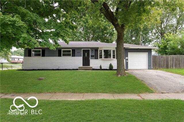 ranch-style house with a garage and a front lawn