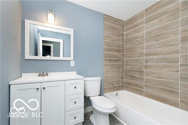 full bathroom featuring tiled shower / bath combo, vanity, and toilet