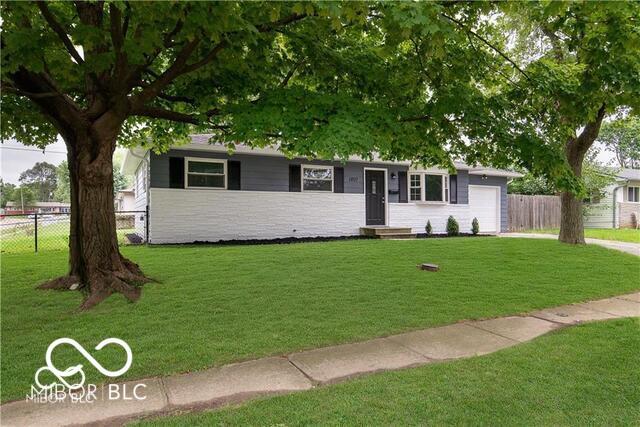 single story home with a garage and a front lawn