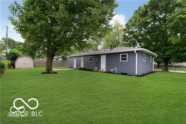 rear view of house with a shed and a lawn