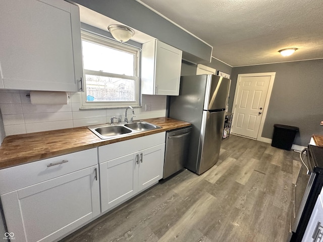 kitchen featuring butcher block countertops, sink, appliances with stainless steel finishes, light hardwood / wood-style floors, and white cabinets