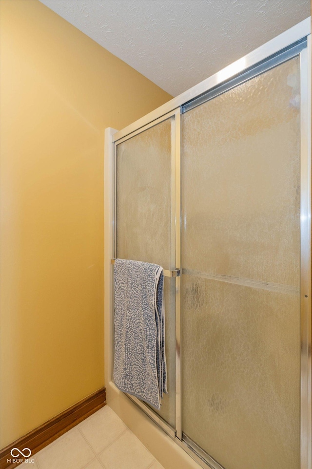 bathroom featuring a shower with door, tile patterned floors, and a textured ceiling