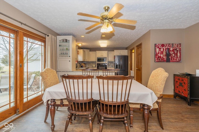 dining space featuring ceiling fan, a textured ceiling, and light wood-type flooring