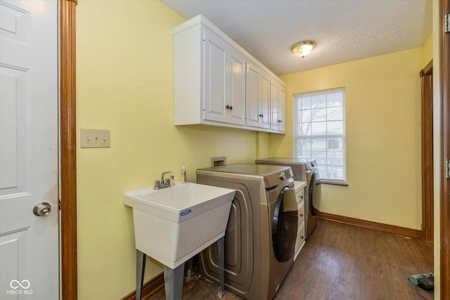 laundry area featuring sink, dark wood-type flooring, washing machine and dryer, cabinets, and a textured ceiling